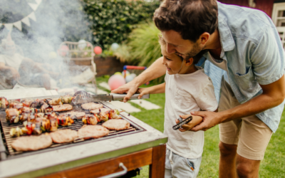 Dad helps child while grilling which shows the importance of fire safety.
