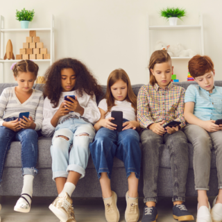 Children sitting o couch together all on phones showing the importance of cyber security for kids.